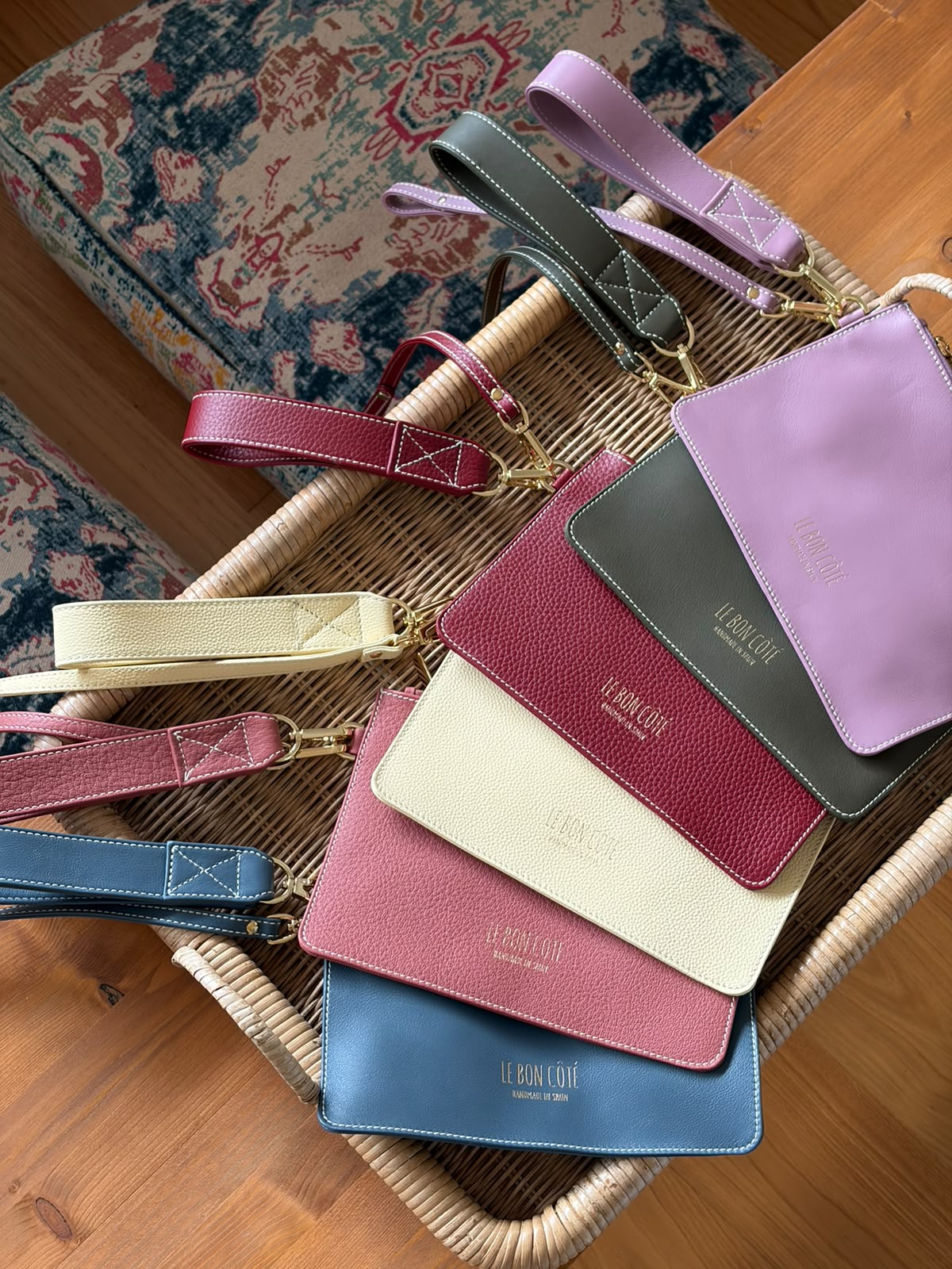 Carteras Domitila en seis tonos de piel sobre una cesta de mimbre